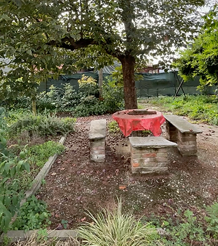 Tavolo da picnic in pietra con tovaglia rossa sotto un albero in un giardino