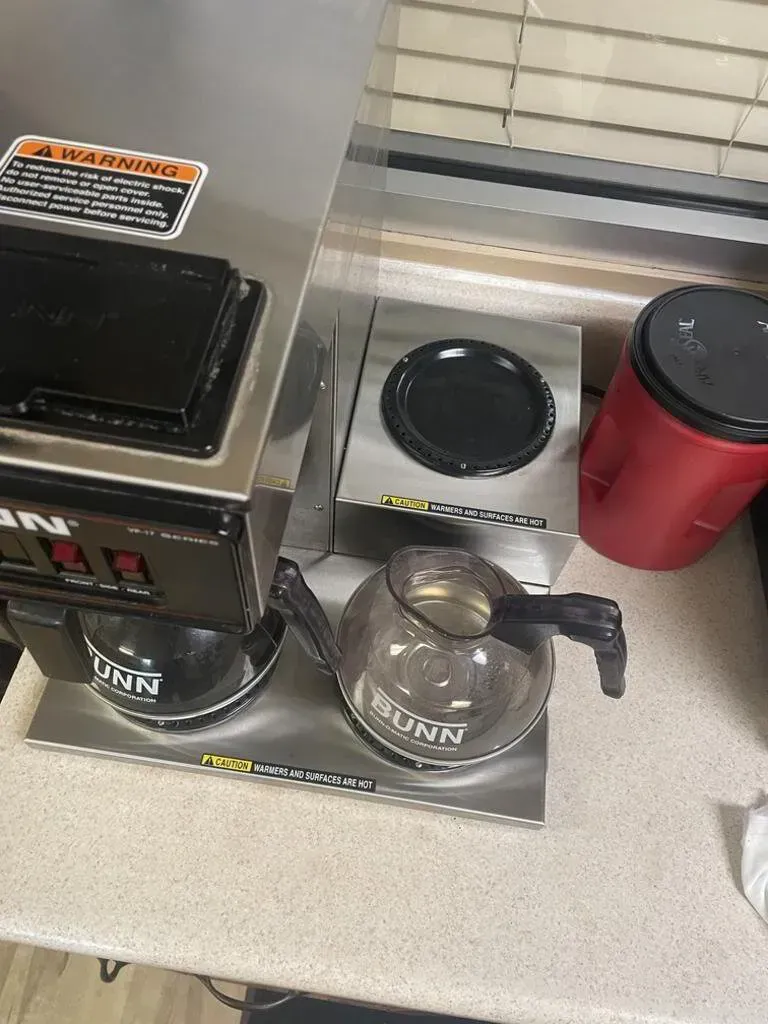 Bunn coffee maker with two pots, a warming plate, and a red insulated coffee dispenser on a countertop.