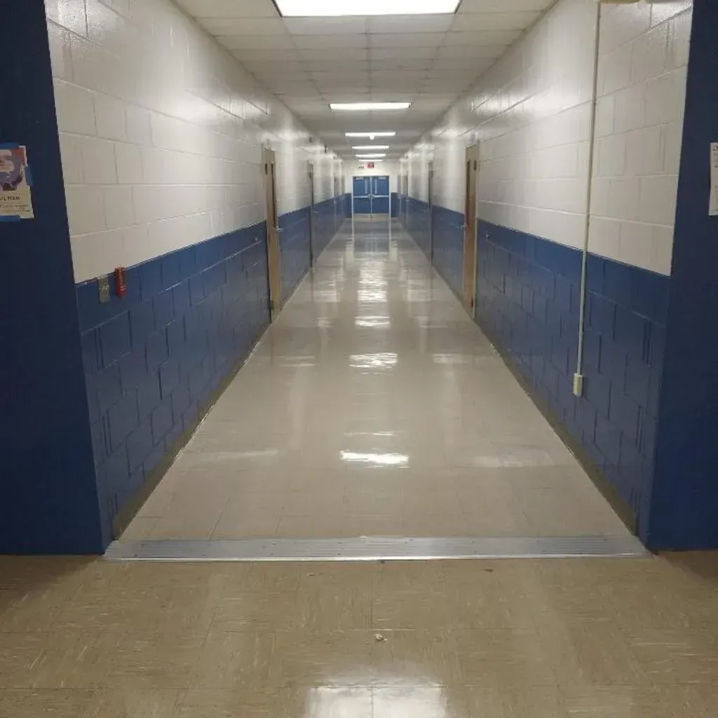 Long, empty school hallway with blue and white walls, and doors on either side.