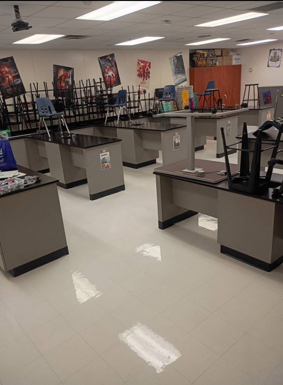 Empty science classroom with lab tables and chairs stacked on desks.
