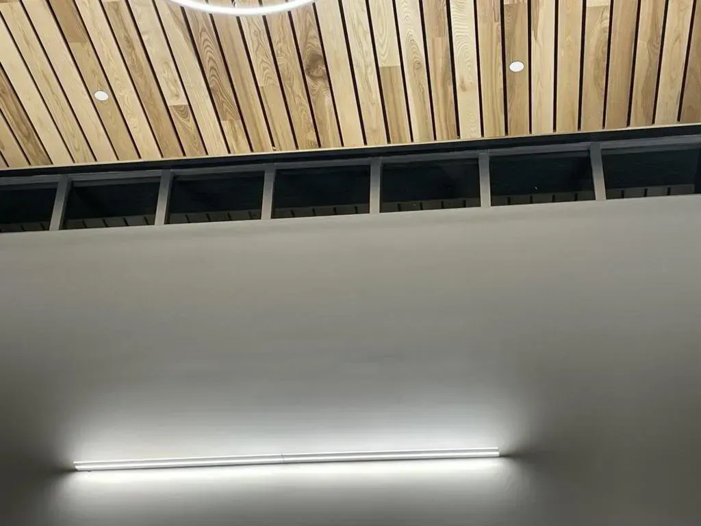 Wooden ceiling, gray wall with a linear light fixture.