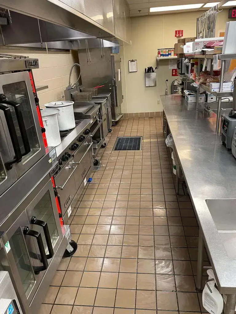 Commercial kitchen interior with stainless steel equipment, tile floor.