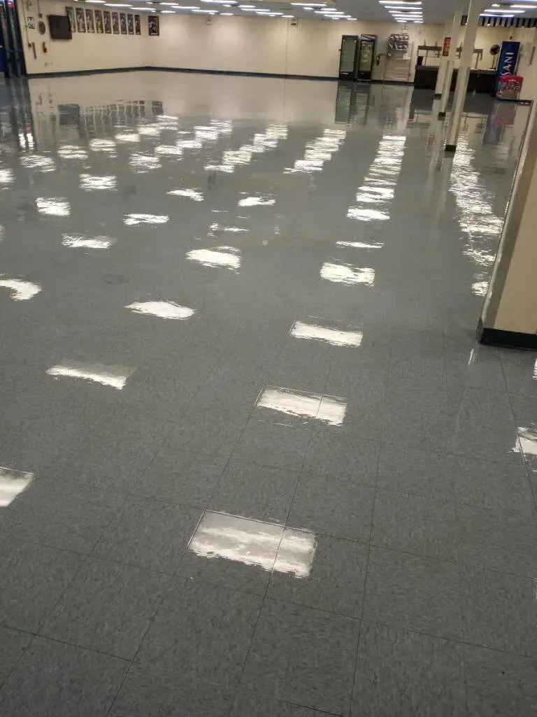 Shiny gray floor reflecting overhead lights in a large, empty room.