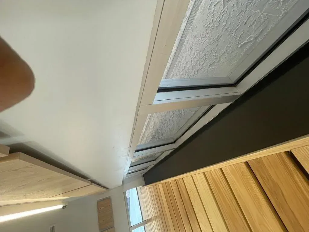 Low-angle shot looking up at a ceiling with wooden panels, white paint, and a dark beam.