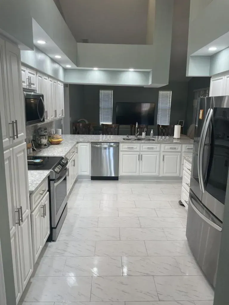 White kitchen with stainless steel appliances and gray countertops.