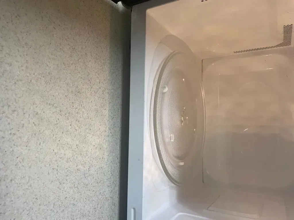 Interior of a microwave. A clear glass turntable sits in the center of the white interior.