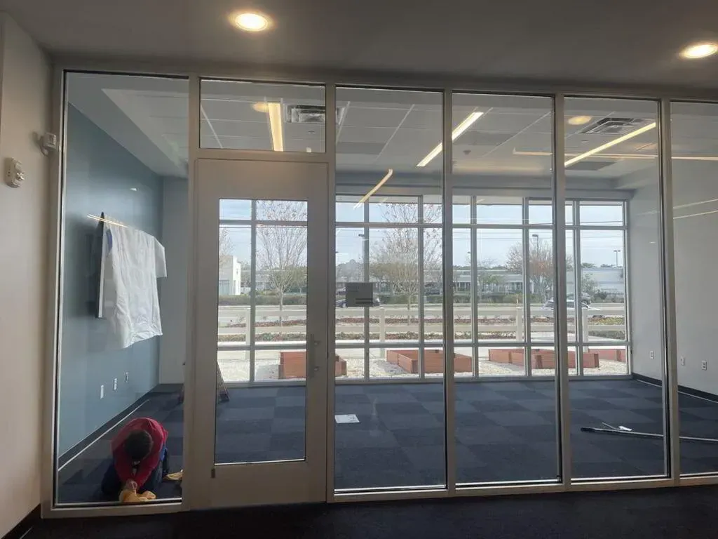 Interior office space with glass walls, door, and a person working on the floor.
