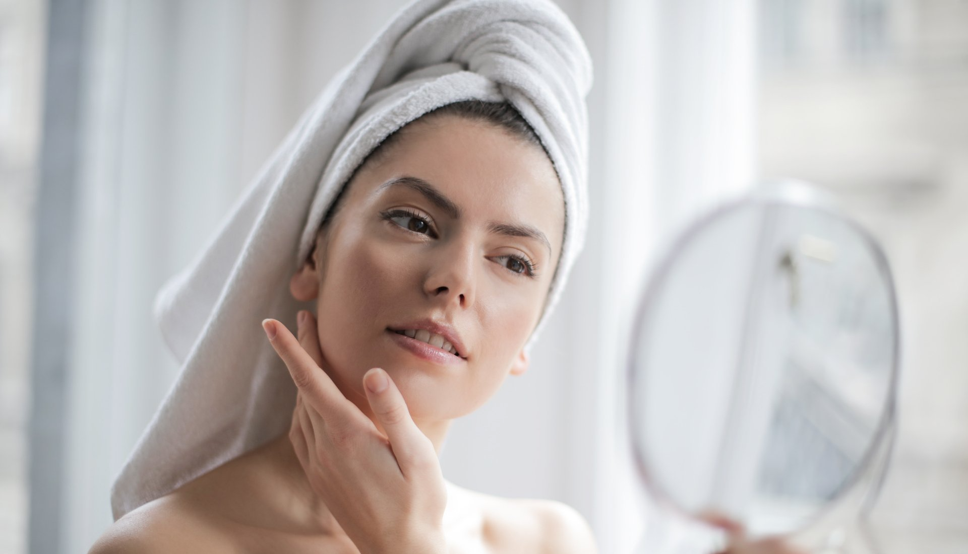 woman looking in mirror with towel on head