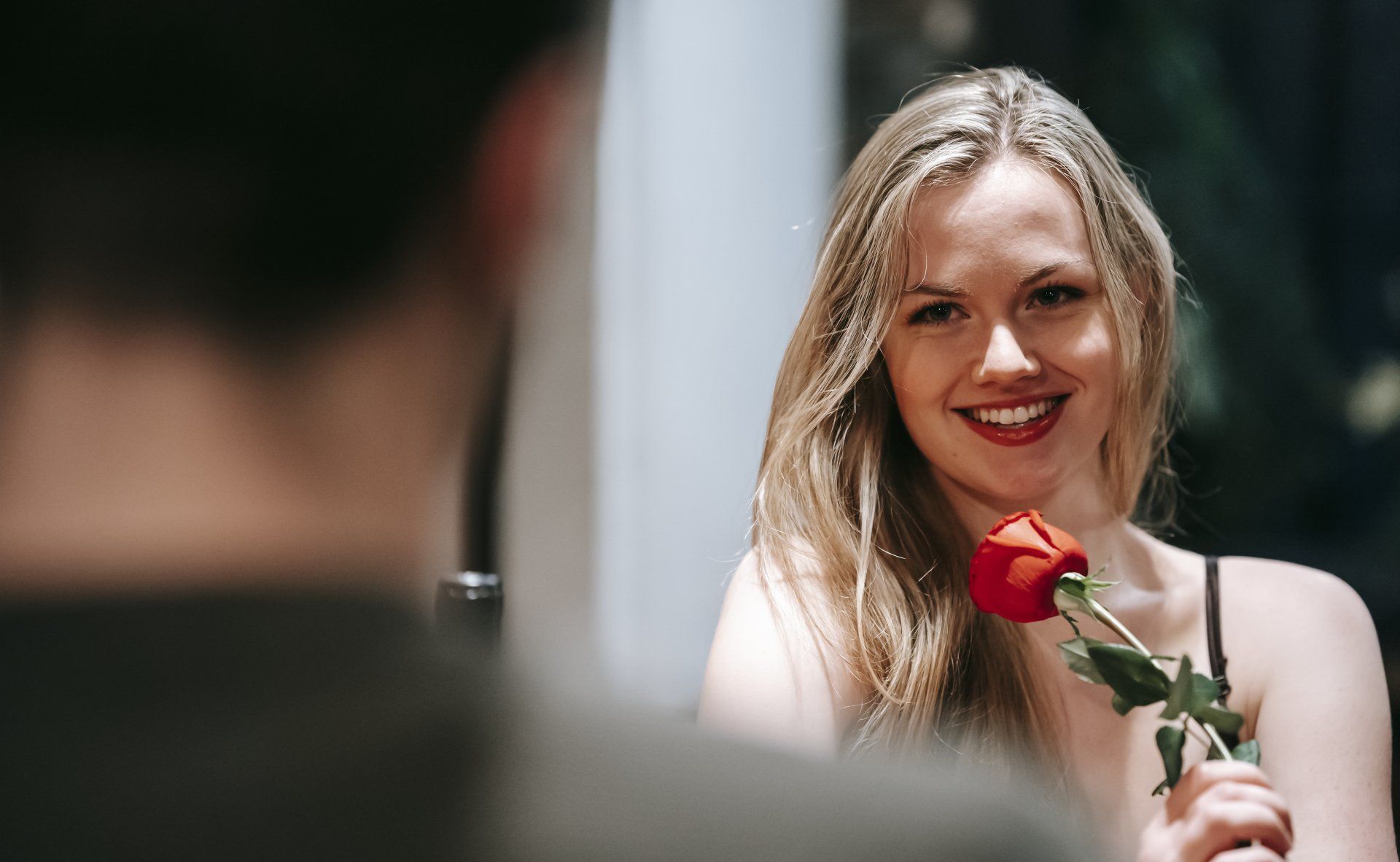 woman holding a rose looking at a man