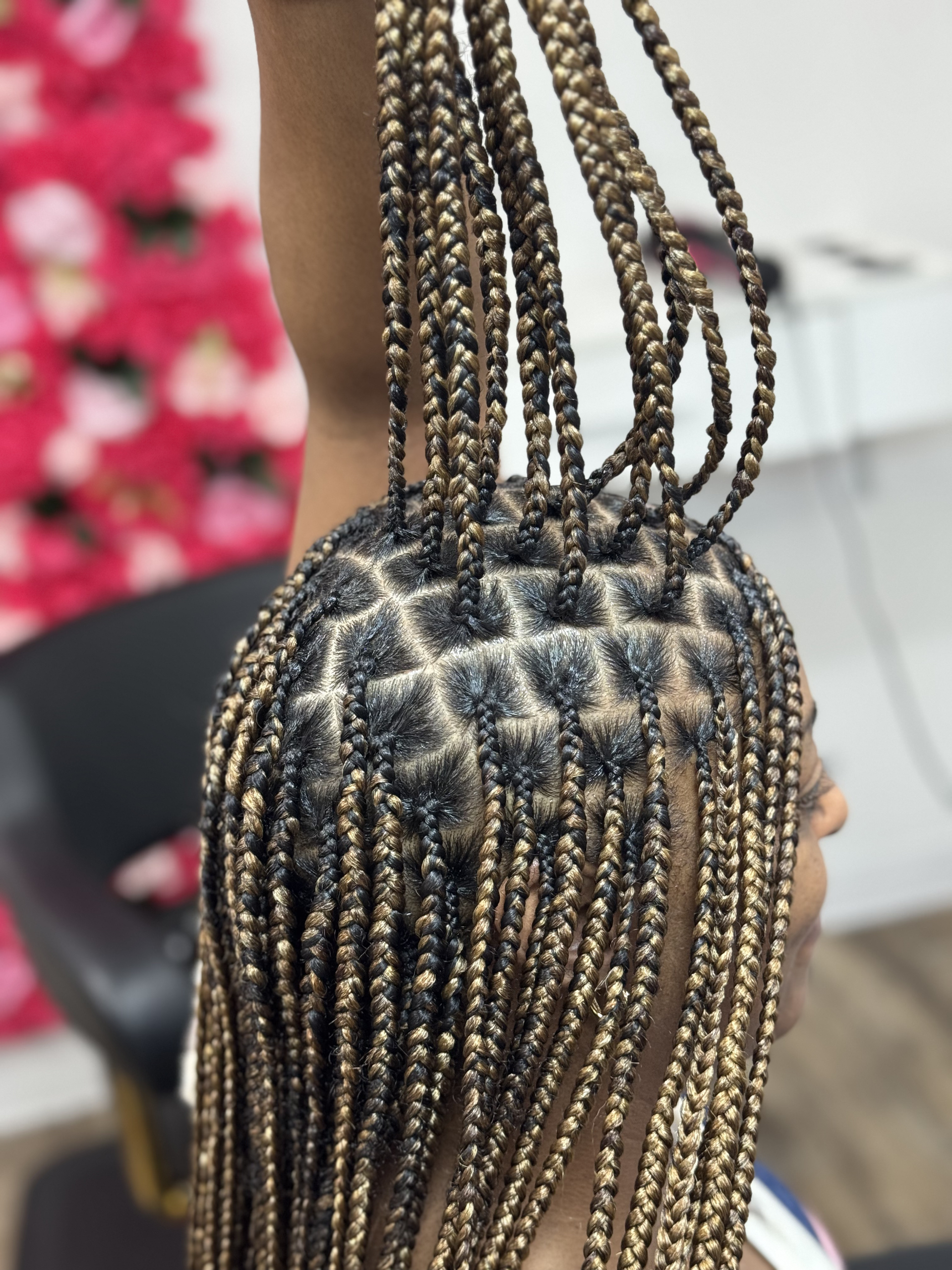 Close-up of braided black hair with orange highlights against a blurred background