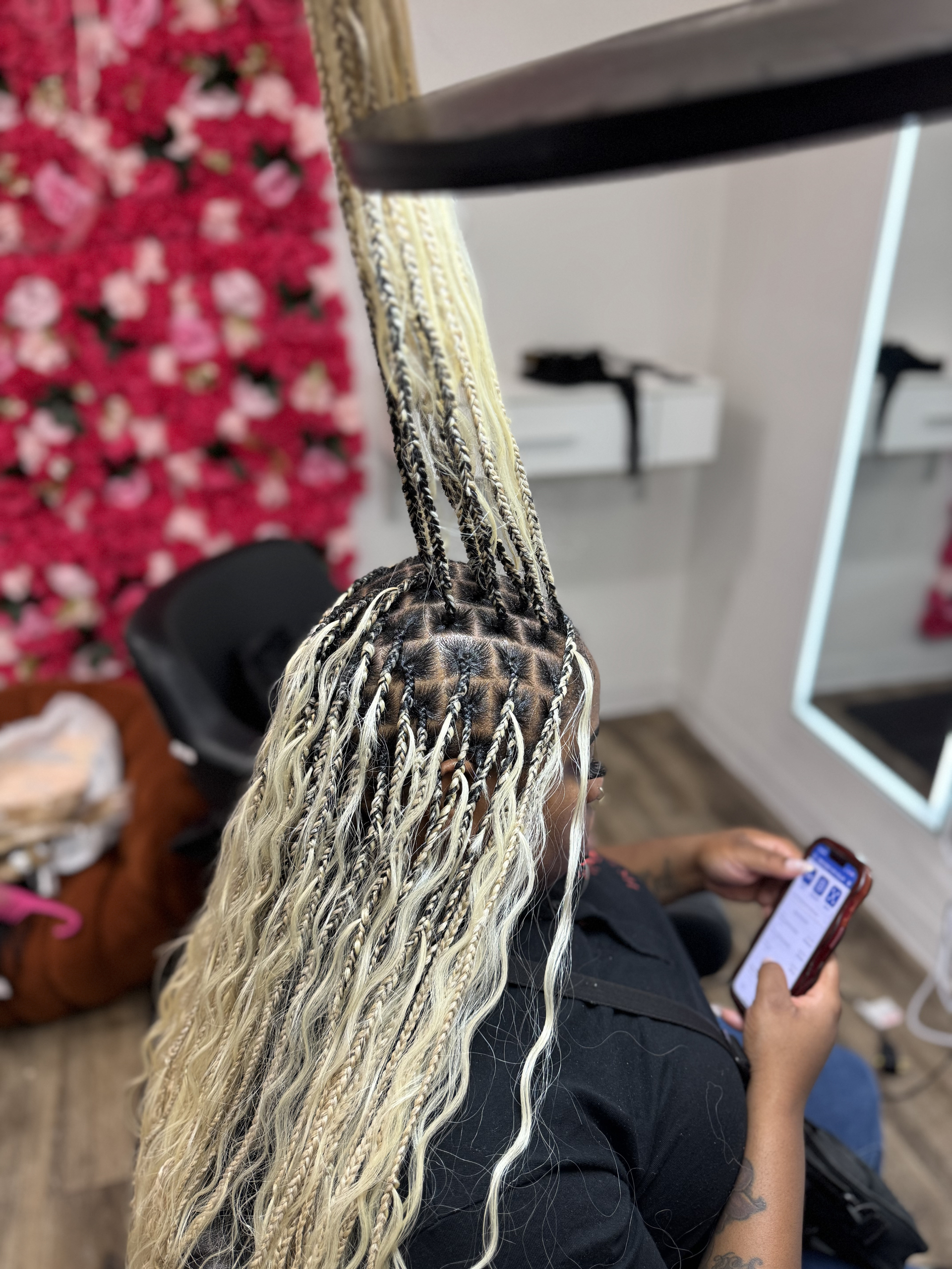 Hands braiding long dark hair with a purple ribbon against a dark background