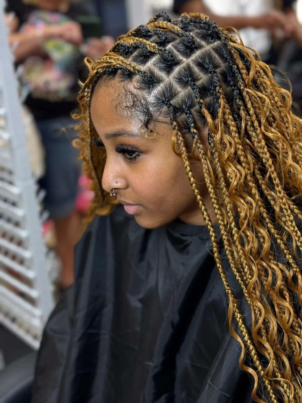 Side-profile portrait of a person with long braided hair wearing a black salon cape