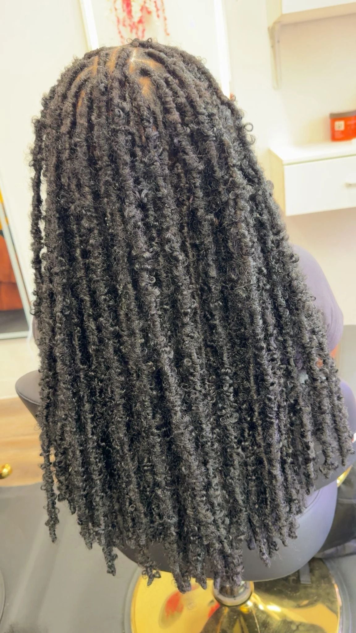 Close-up of long, tightly twisted black hair falling down the back in a salon setting