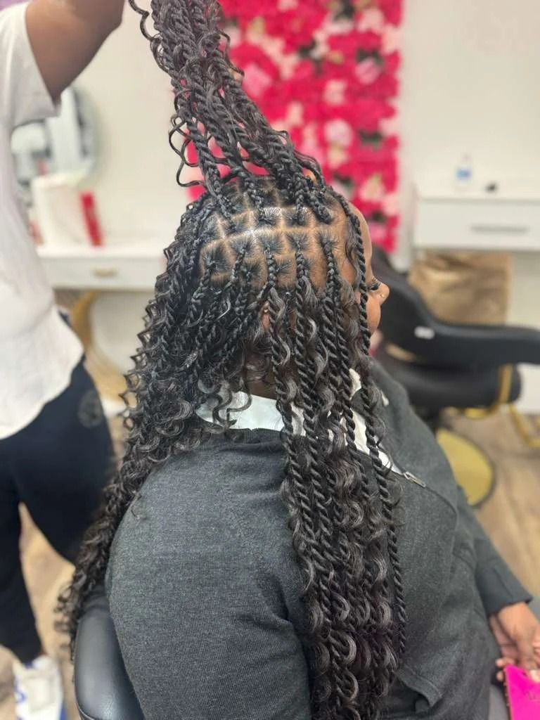 Person in a salon chair with braided hair being styled by a stylist