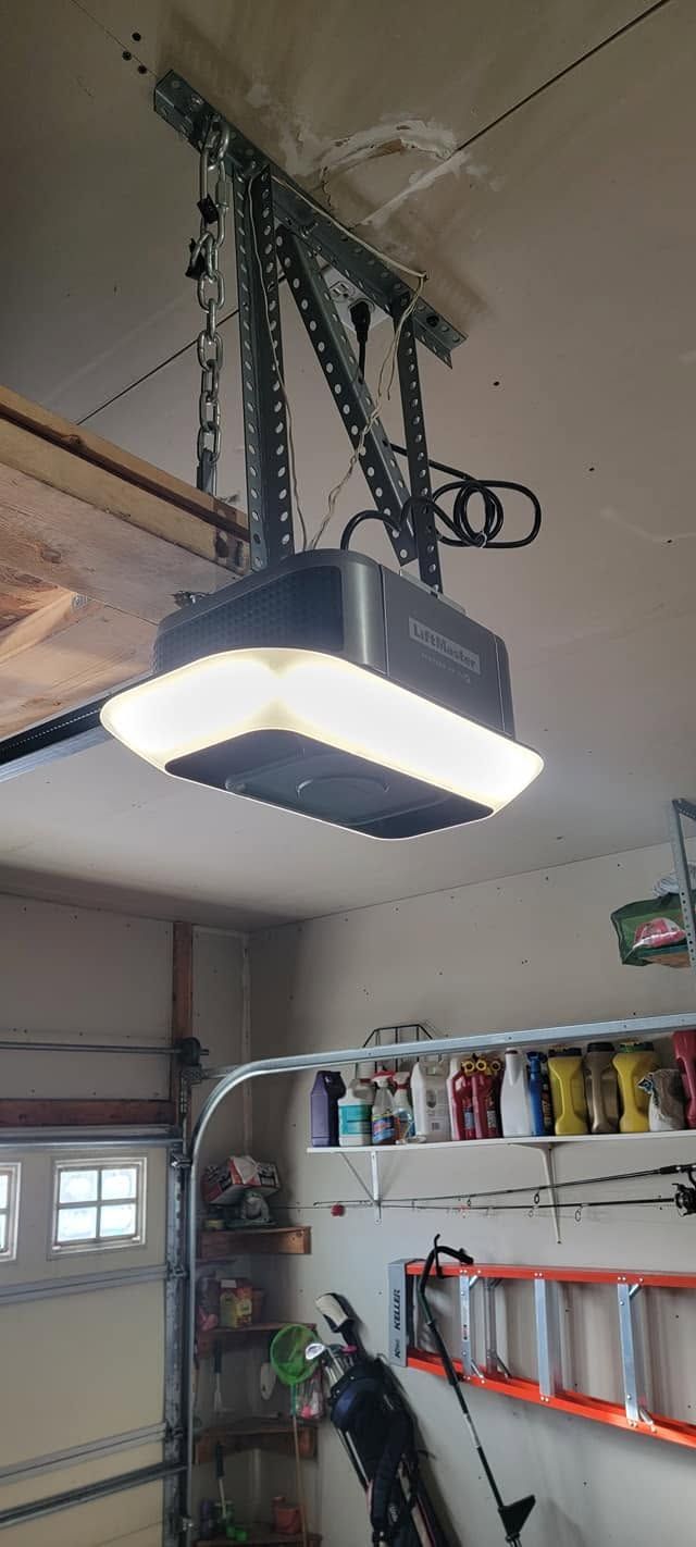 Garage ceiling mounted overhead door opener with a lit rectangular light panel.