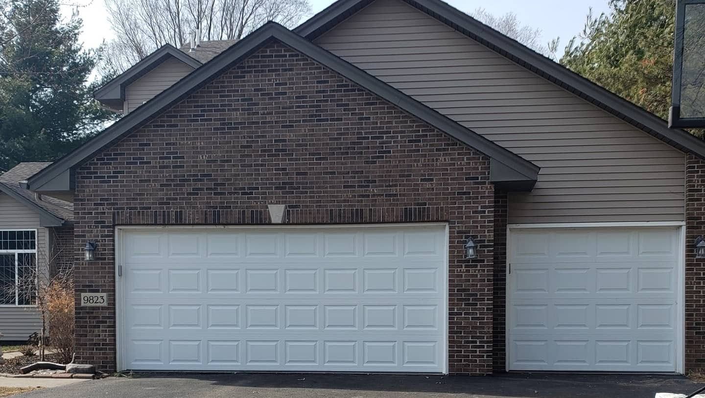Brick house with white two-car garage and smaller side garage door at front entrance