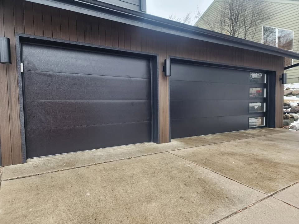 Two dark brown garage doors on a concrete driveway under a sloped roof