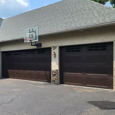 Residential garage with two dark brown doors and a basketball hoop mounted above the left door