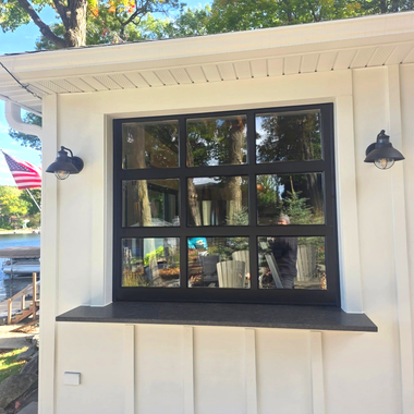 Black-framed window on a white exterior wall with black wall lanterns and a dark sill.