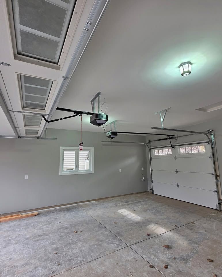 Empty garage interior with white walls, concrete floor, and closed overhead door