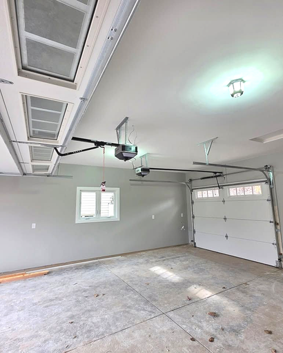 Empty garage interior with white walls, concrete floor, and closed overhead door