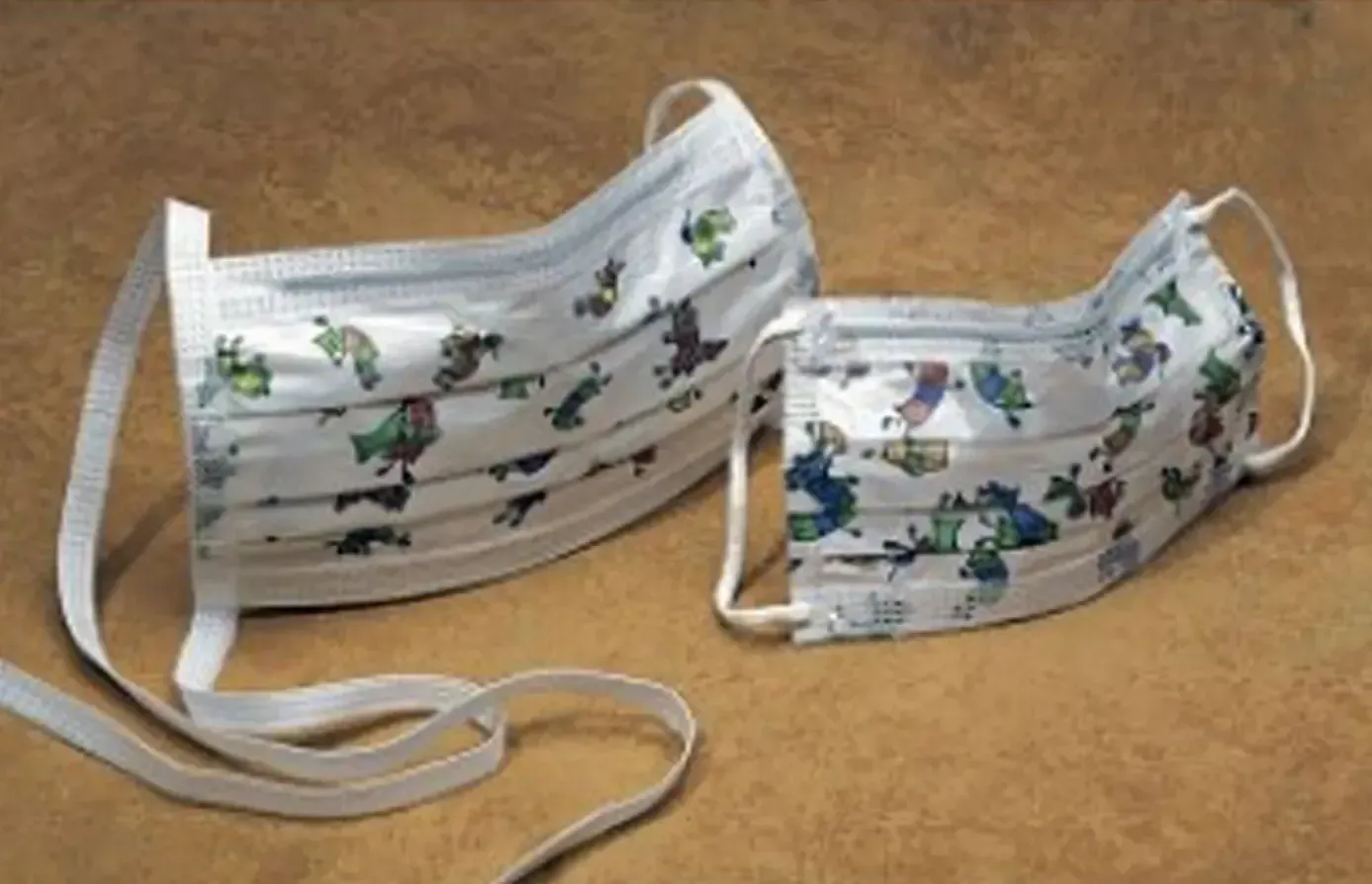 Two floral-patterned pleated face masks on a tan surface