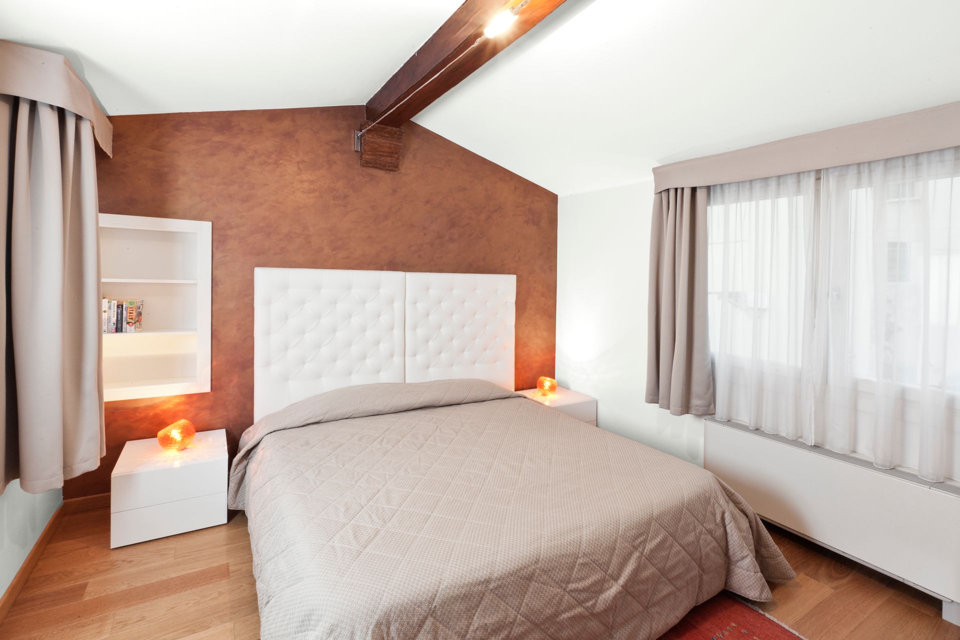 Chambre moderne avec un lit, un mur d'accent marron, des fenêtres avec rideaux et un éclairage chaleureux.