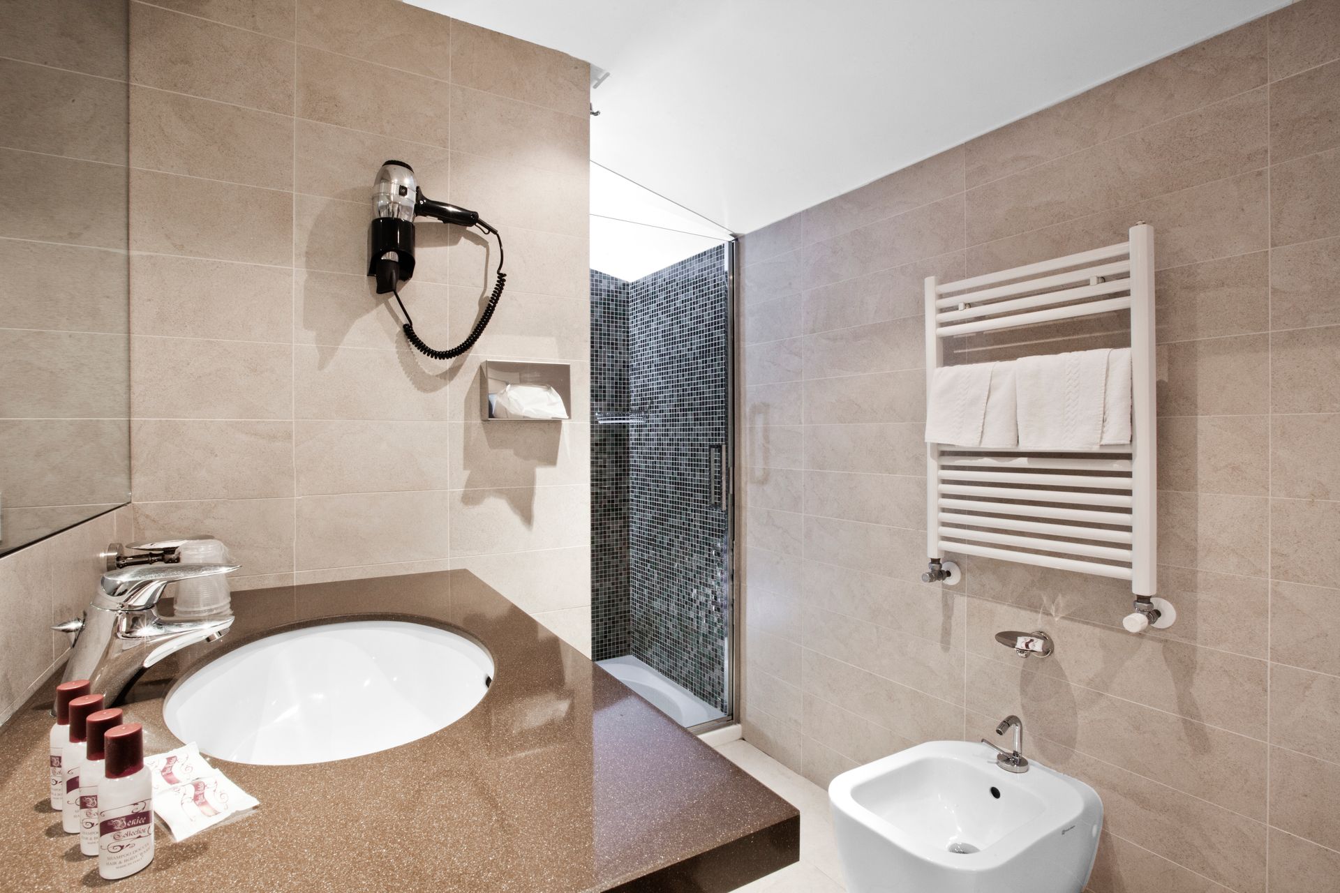 Bagno moderno color beige con lavabo, doccia, portasciugamani e specchio a parete.