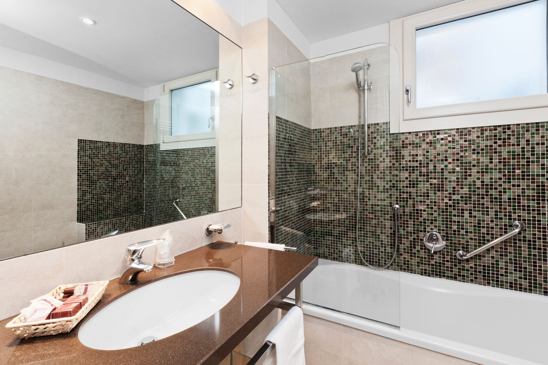 Modernes Badezimmer mit braunem Waschtisch, großem Spiegel, Mosaikfliesenwand und weißer Badewanne/Dusche.