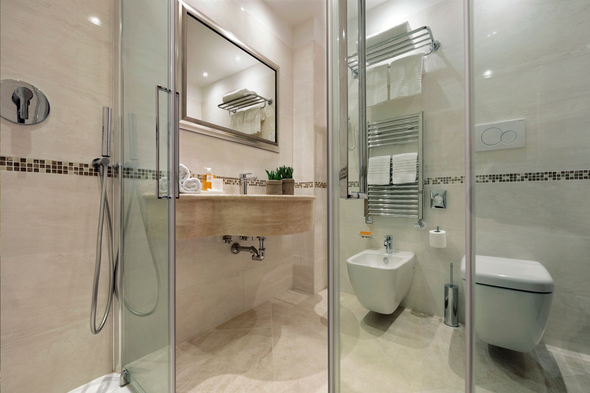 Bagno moderno con doccia in vetro, lavabo a parete e WC nei toni del beige.