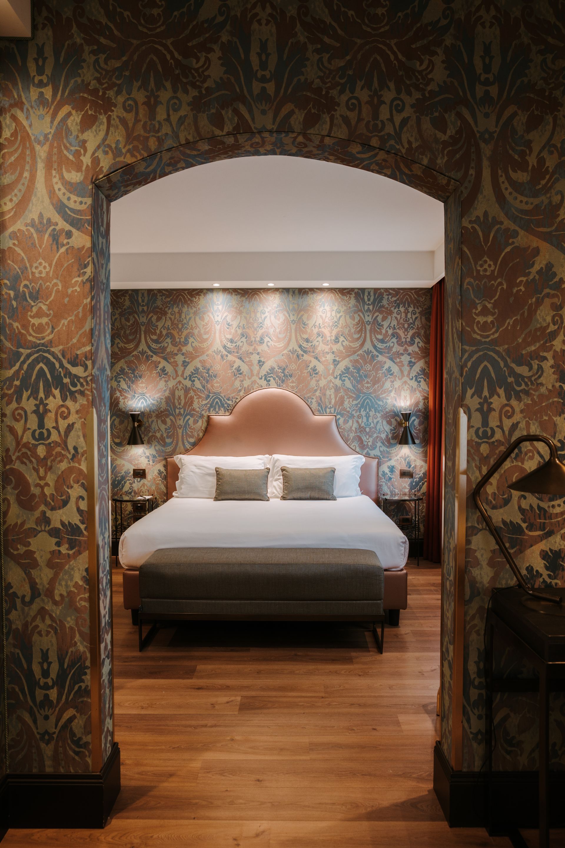 Accogliente camera da letto incorniciata da un arco decorato, con un letto ben rifatto e caldi pavimenti in legno.