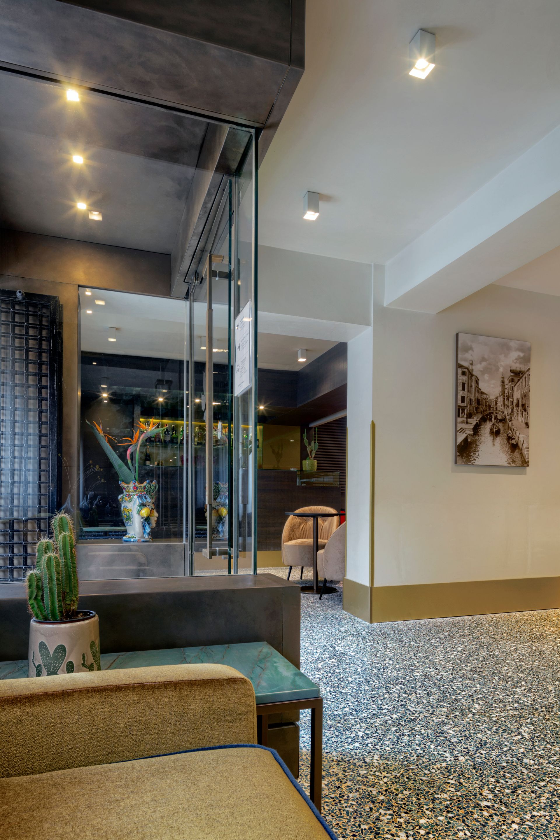Moderne Lobby mit gesprenkeltem Boden, Glaswand, Hängelampen und einem kleinen Kaktuspflanzgefäß