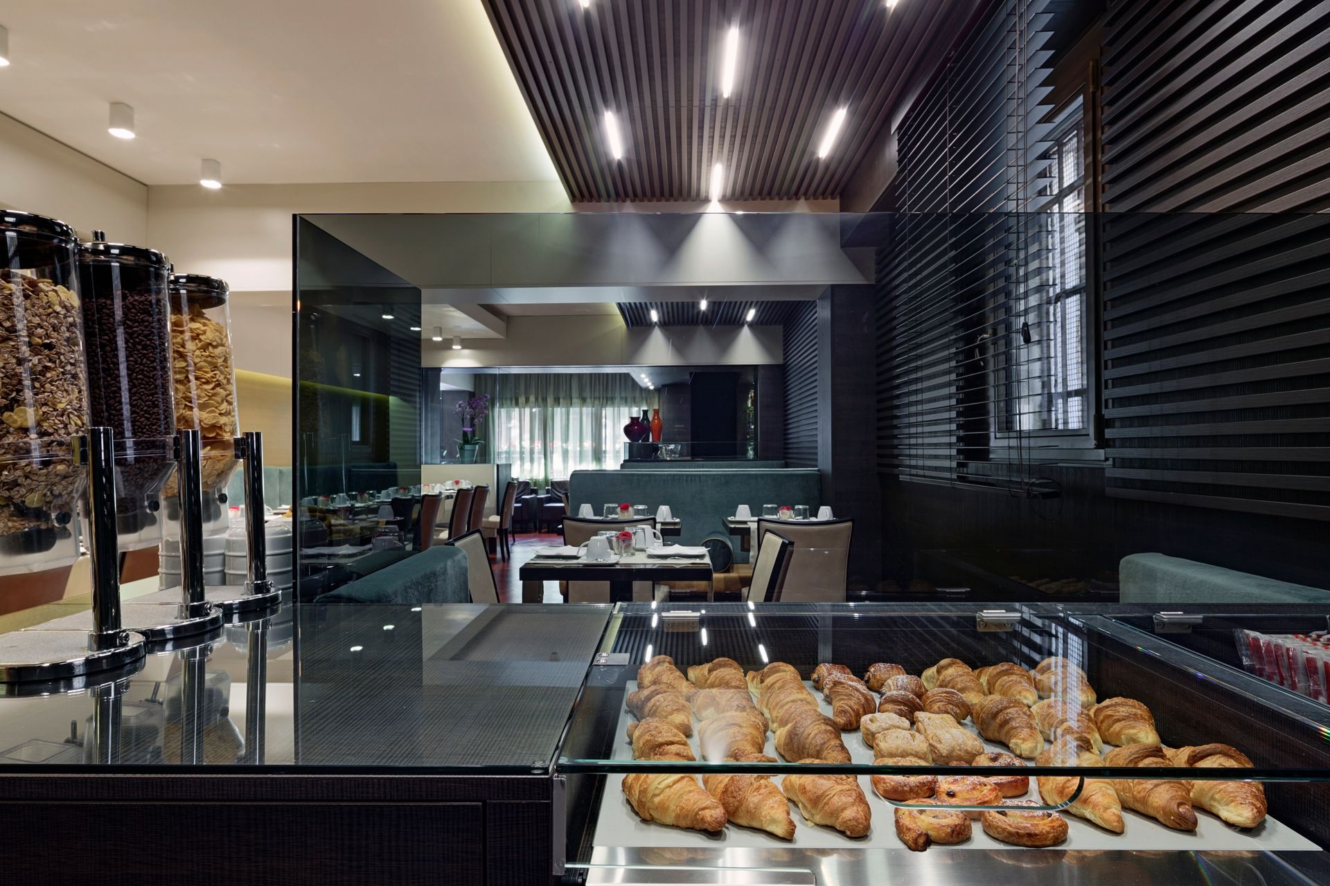 Bancone buffet moderno con pasticceria, vetrina e interni eleganti e scuri della sala da pranzo.