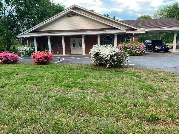 Single-story house with a front porch, flower beds, and a parked SUV in the driveway