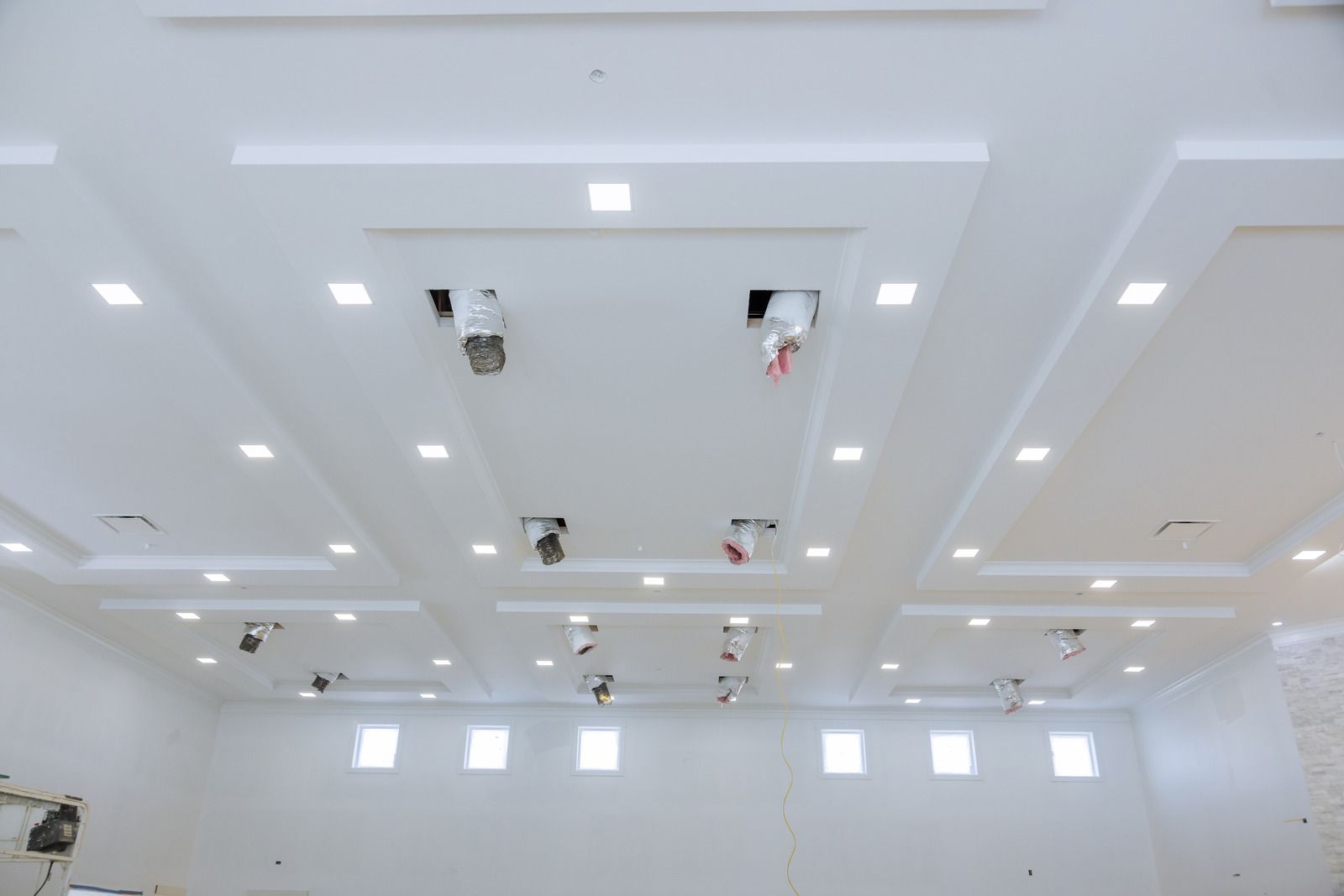 White ceiling with recessed lighting and several hanging lights in a room.