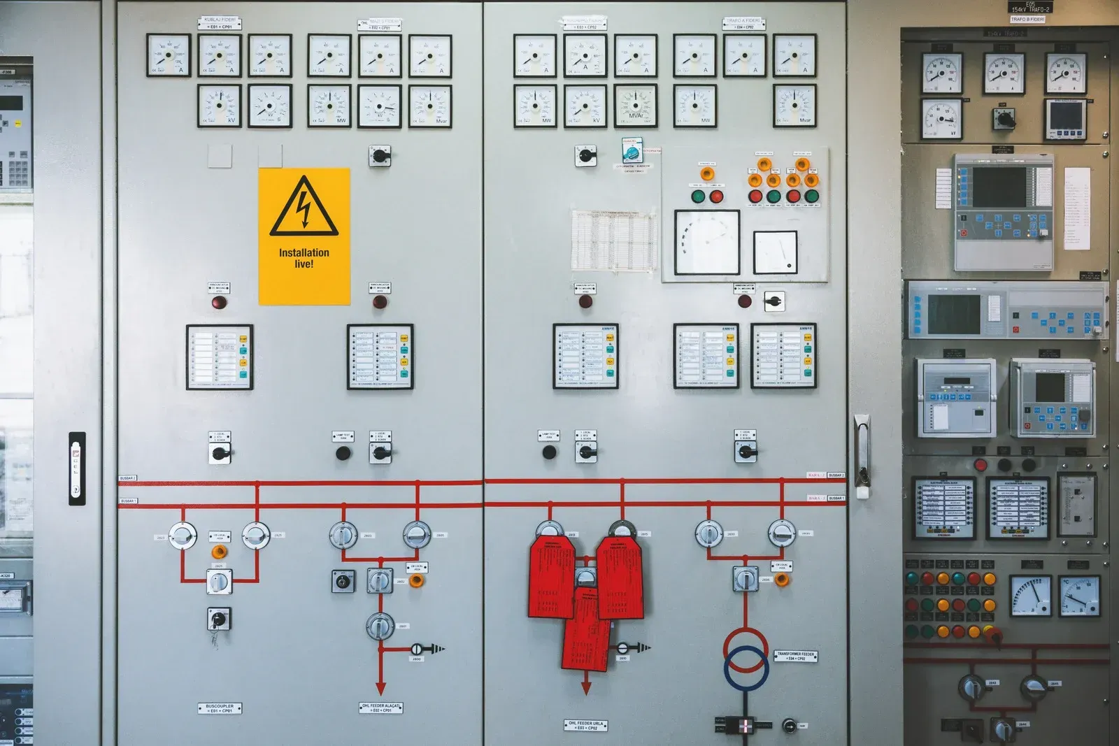 Electrical control panel with numerous gauges, buttons, and warning sign.