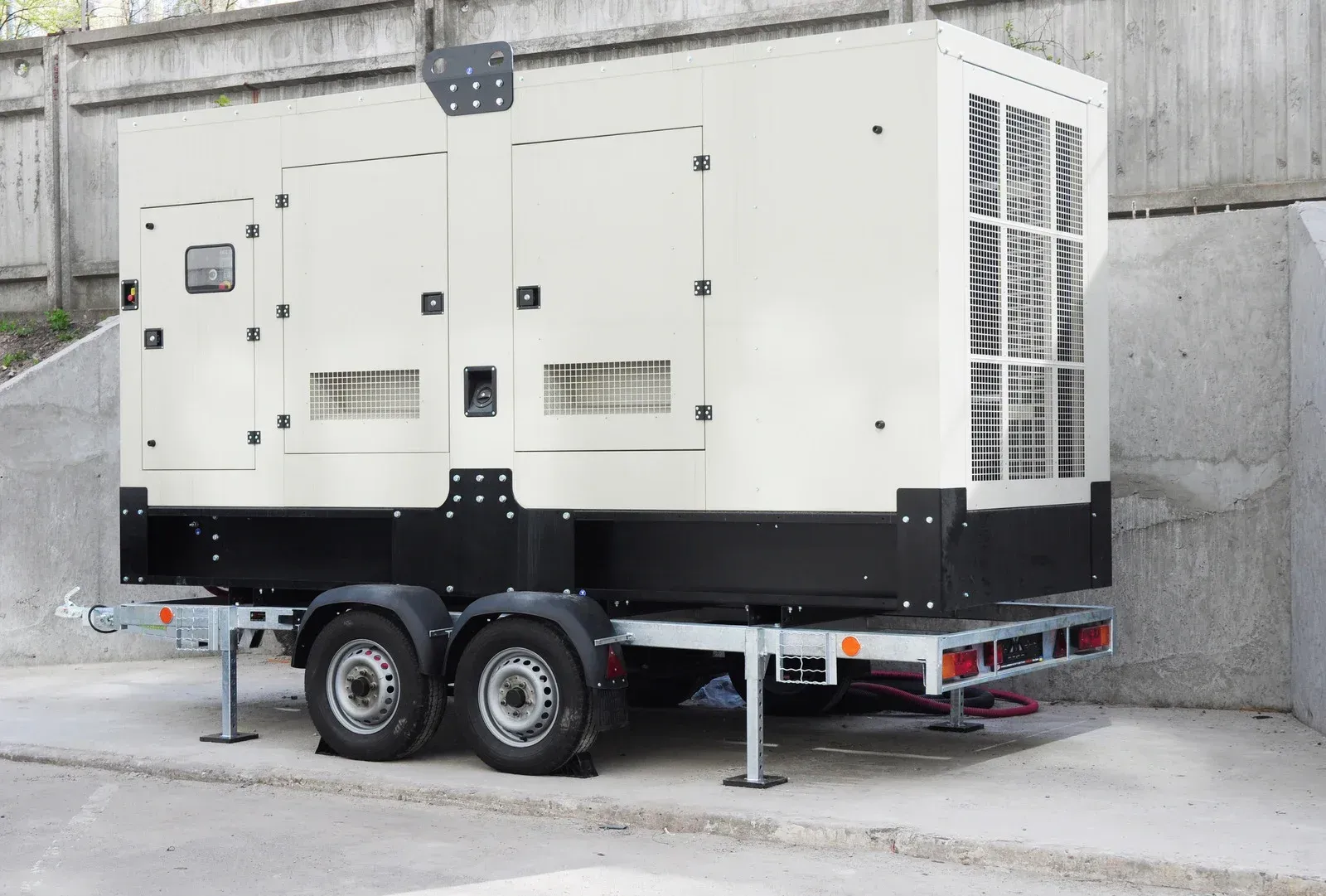 Green and black generator outside a building entrance, snowy ground.