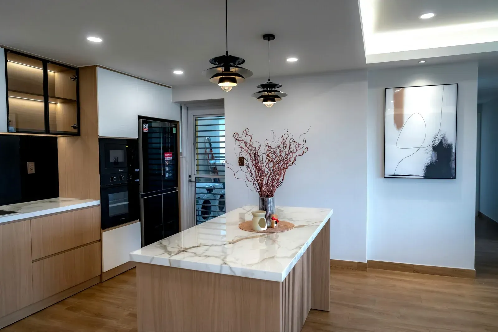 Modern kitchen with wood cabinets, marble island, and abstract art.