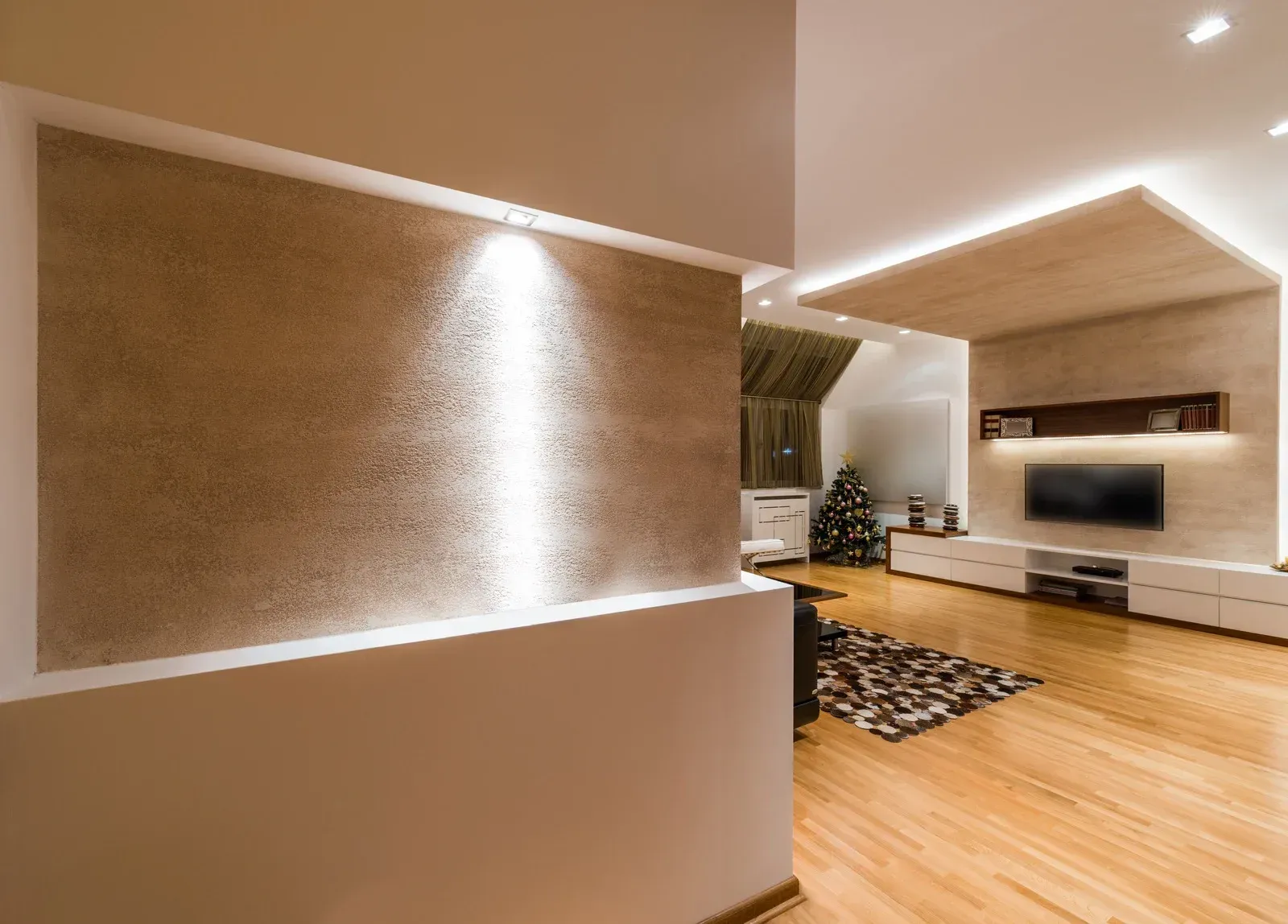Modern living room with textured wall, recessed lighting, and wooden floors.