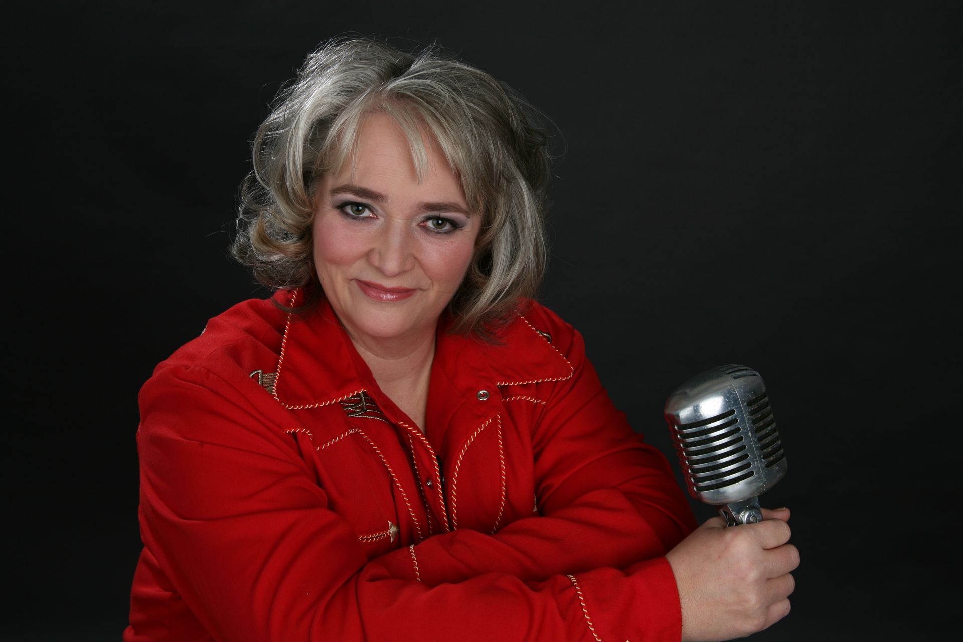 Frau in rotem Hemd lächelt und hält ein Vintage-Mikrofon.