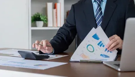 Businessperson reviewing charts at a desk with a calculator and papers