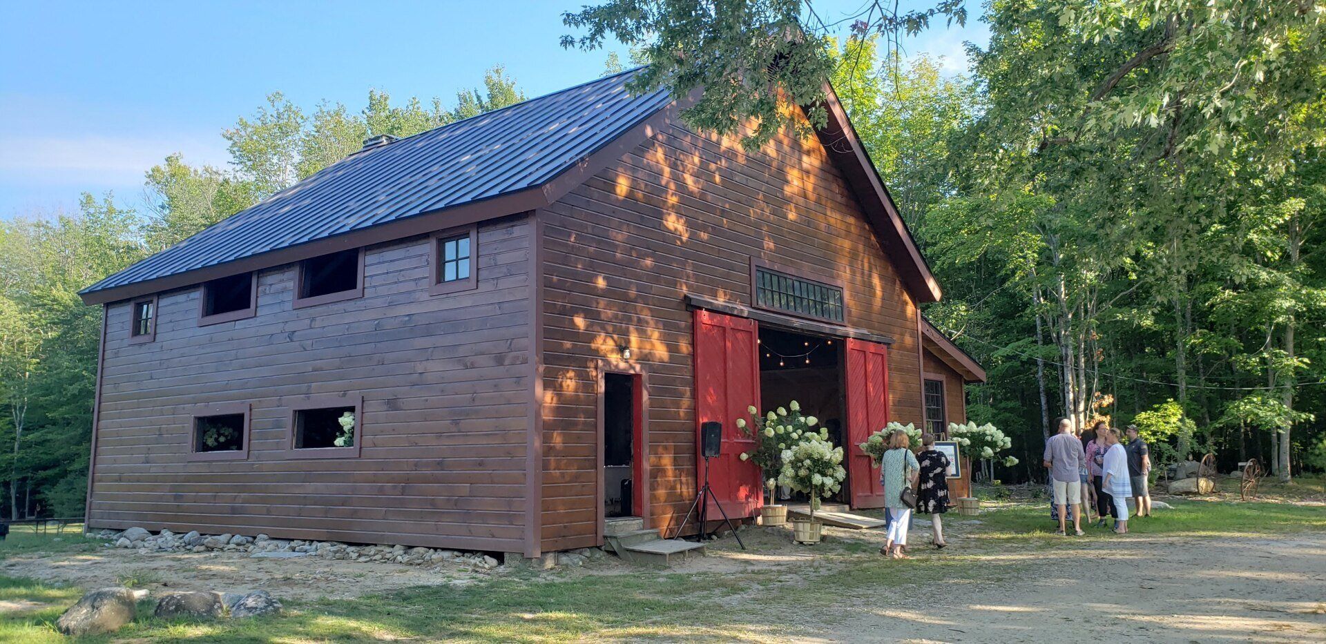 A group of people are standing in front of a large wooden barn.