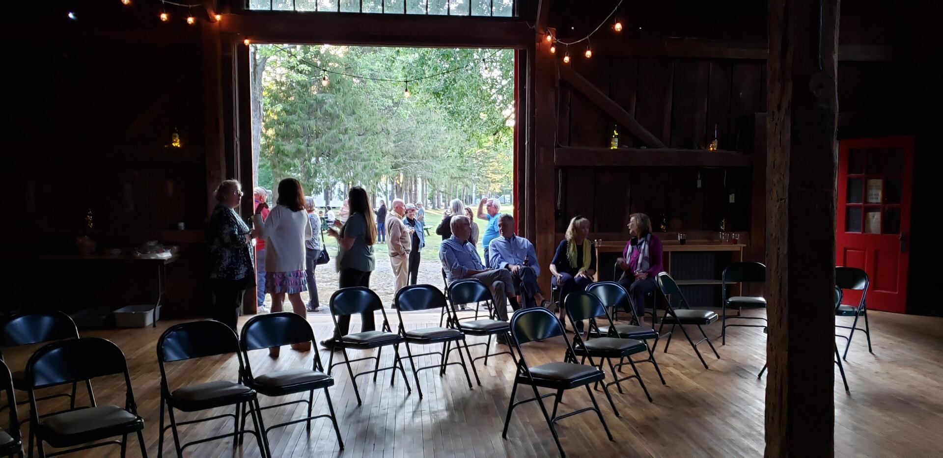 A group of people are sitting in chairs in a barn.