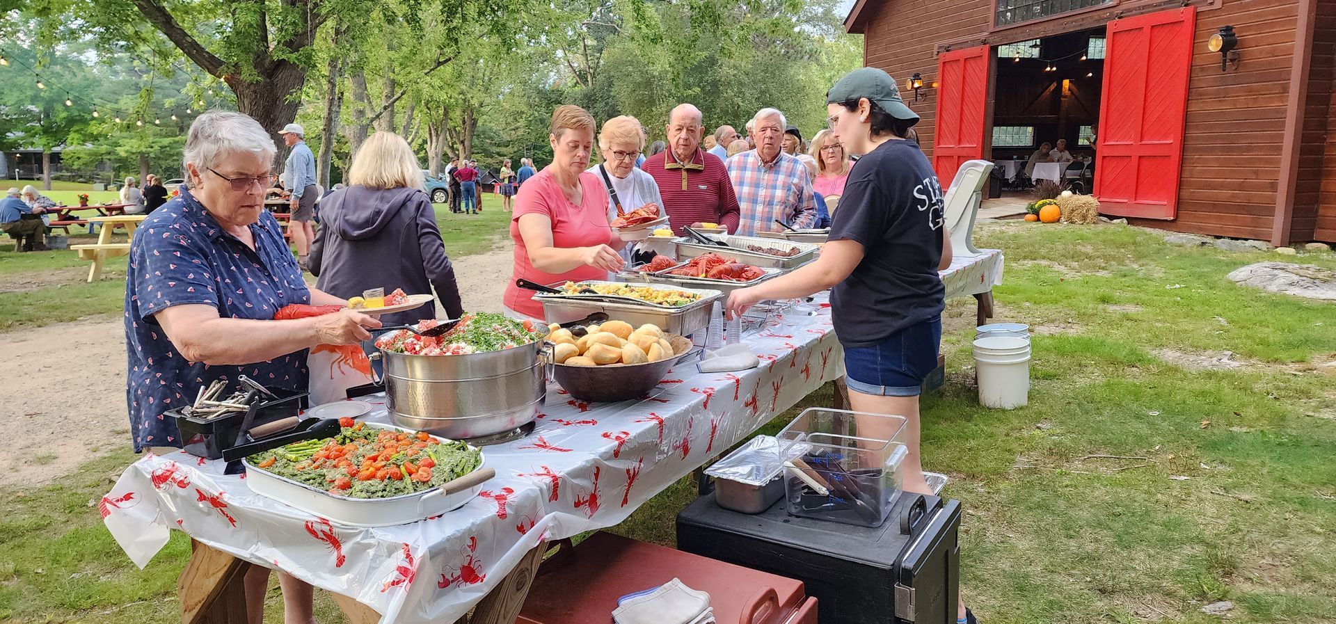 A group of people are standing around a table filled with food.