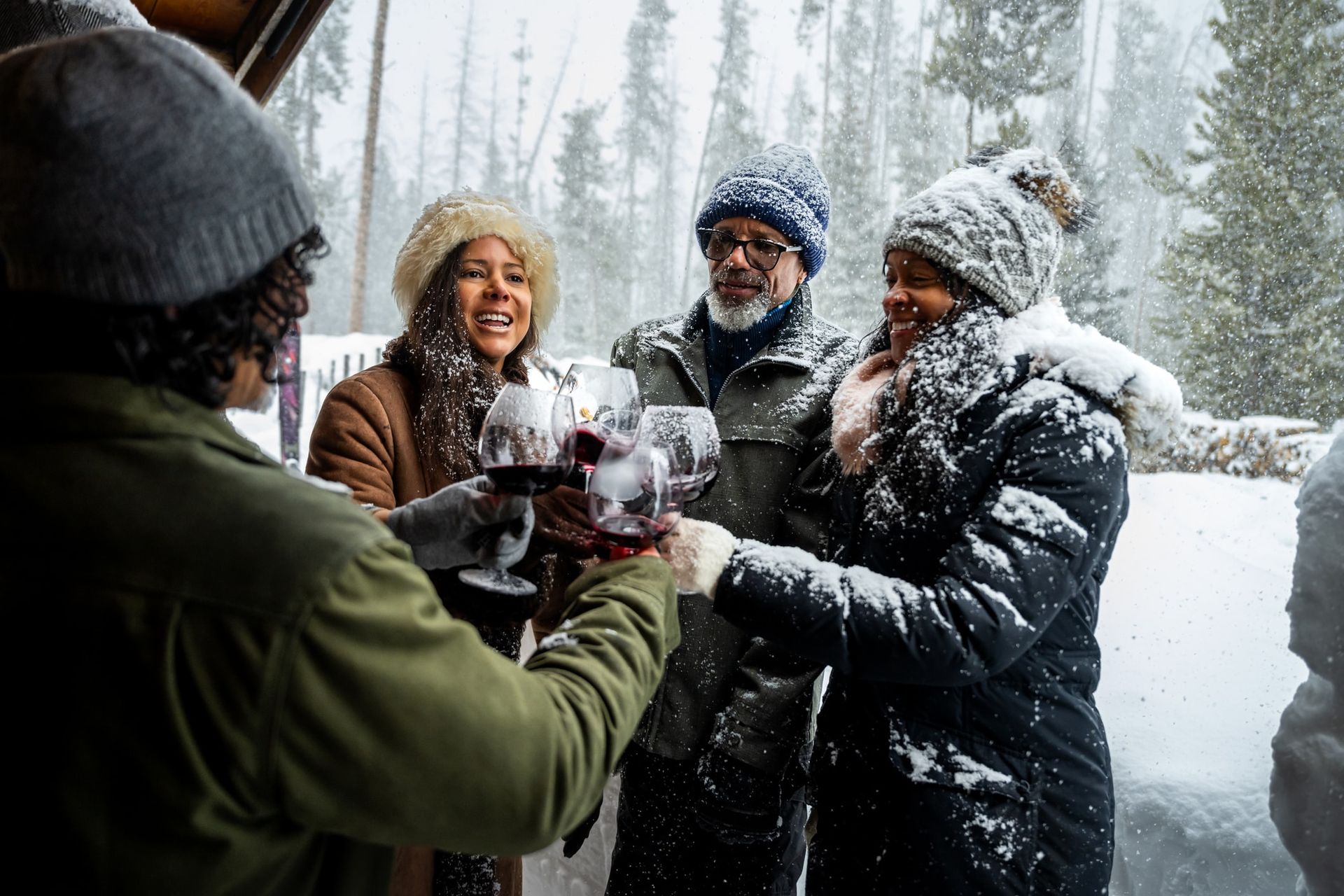 A group of people are toasting with wine glasses in the snow.
