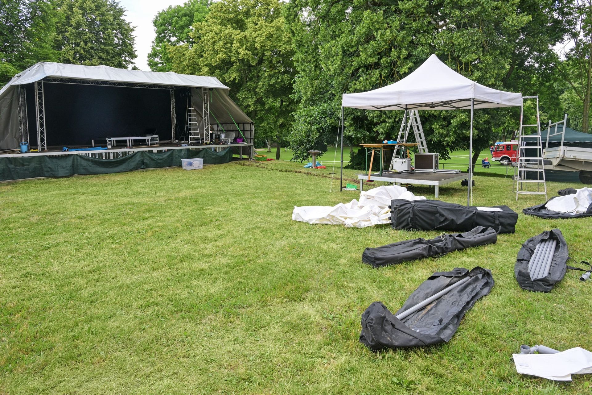 A large grassy field with a stage and tents in the background.