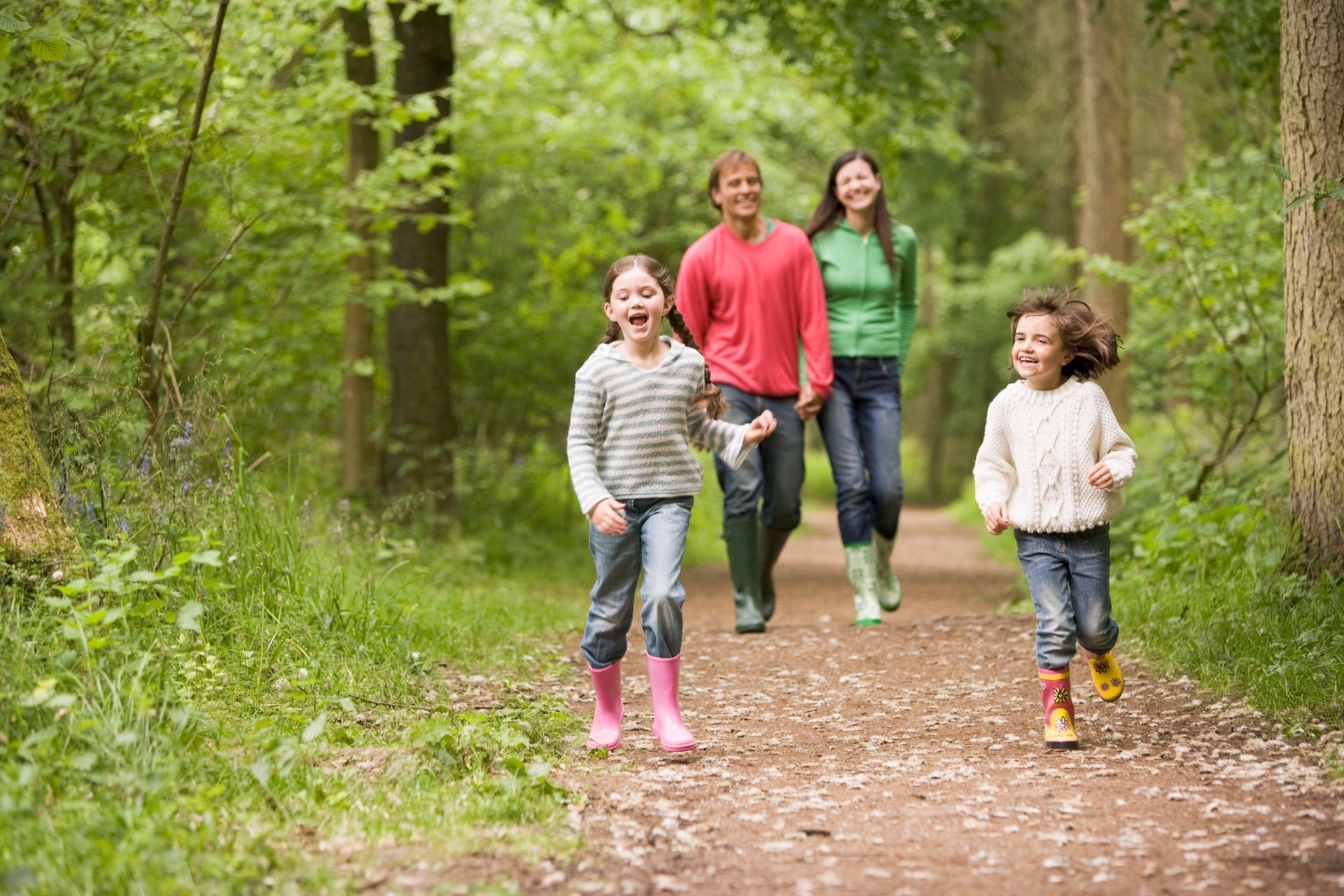 A family is walking down a path in the woods.