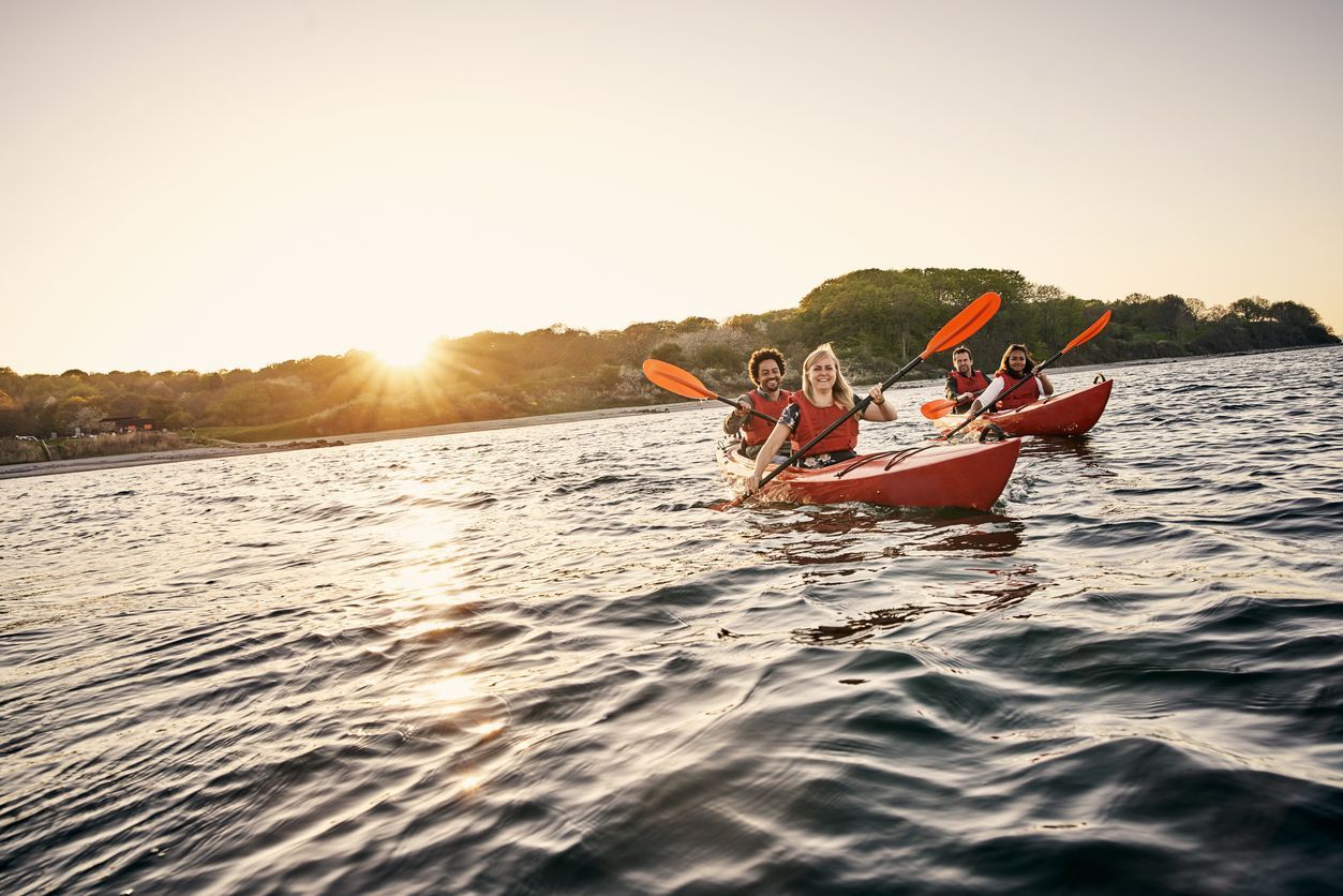 A group of people are kayaking on a lake at sunset.