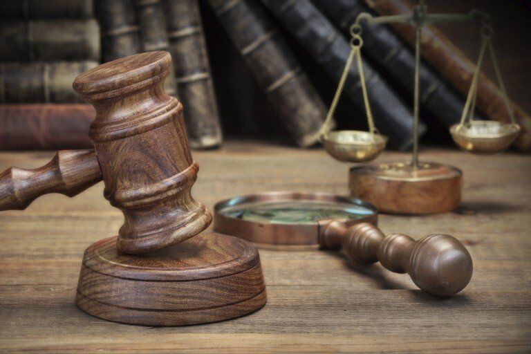 Gavel next to magnifying glass and justice scale