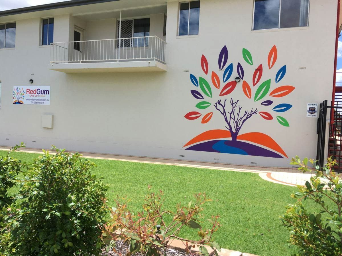 Building exterior with mural of a colourful tree, balcony, and green lawn — Signvision In Dubbo, NSW